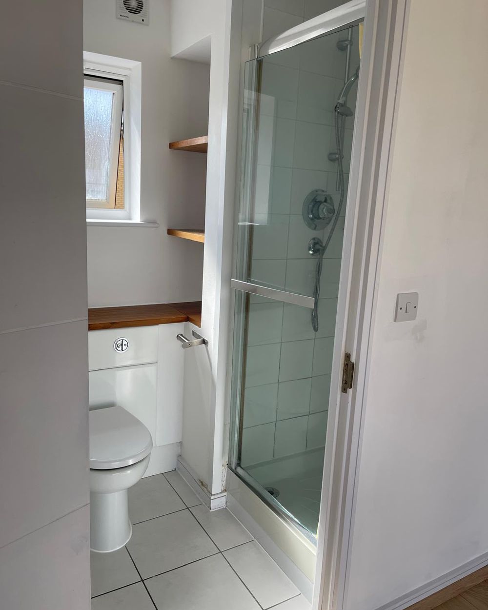 Clean shower room with glass door and white tiles